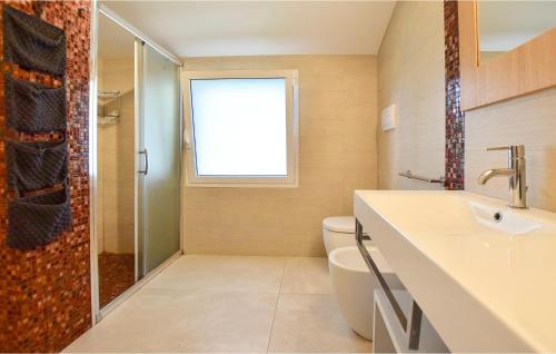 a bathroom with a toilet and a sink and a window at Villa Elite 2 in Marina di Ragusa