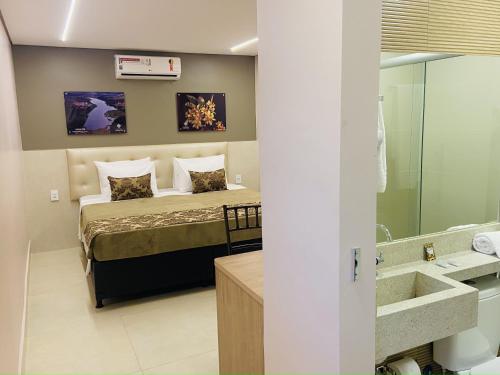 ein Schlafzimmer mit einem Bett und ein Badezimmer mit einem Waschbecken in der Unterkunft Hotel Conviver in Formosa