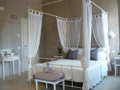 1 dormitorio con cama blanca con dosel y silla en Dolcedimora, en Appignano