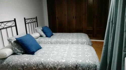 2 łóżka pojedyncze z niebieskimi poduszkami w pokoju w obiekcie CASA MI SUEÑO w mieście Grazalema