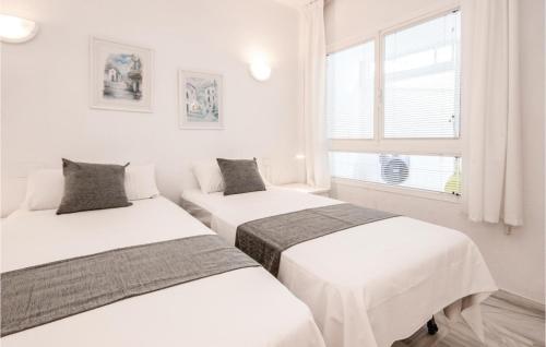 two beds in a white room with a window at Nice Apartment In Calahonda With 2 Bedrooms, Wifi And Outdoor Swimming Pool in Sitio de Calahonda