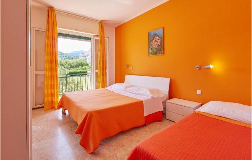 2 letti in una camera con pareti arancioni e finestra di Casa Borgo 2 a Pietra Ligure