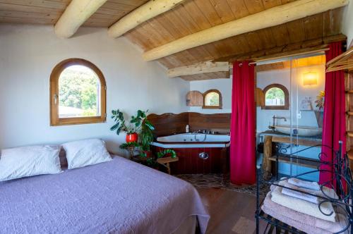 Maison de charme avec piscine et jacuzzi في Pino: غرفة نوم مع سرير وحوض استحمام ومغسلة