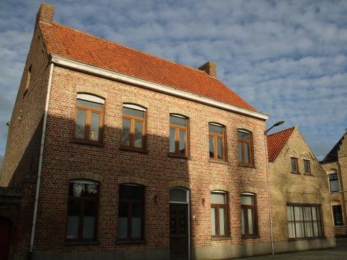 a brick building with a red roof at B&B Herenhuis1919 in Lo-Reninge