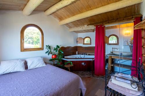 a bedroom with a bed and a tub and a sink at Coin de paradis vue dominante sur mer, montagne et tour génoise avec jacuzzi in Pino