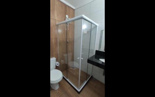 a bathroom with a toilet and a glass shower at SUITES PRAIA GRANDE in Arraial do Cabo