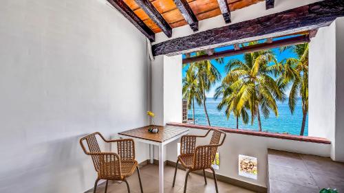 a table and chairs in a room with a view of the ocean at Marboka Hotel & Suites in Puerto Vallarta