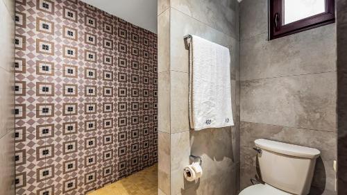 a bathroom with a toilet and a tile wall at Marboka Hotel & Suites in Puerto Vallarta