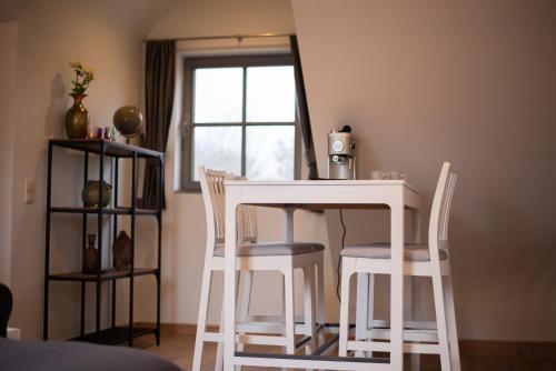 a white table and chairs in a room with a window at Domein Den Buiten Bed And Breakfast DnD in Sint-Niklaas