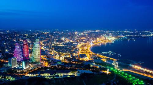 a view of a city at night with the ocean at MidCity Hotel in Baku