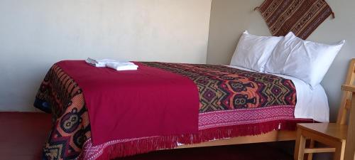 Habitación de hotel con cama con manta roja en Alberto homestay taypi qamaña establo en Juli