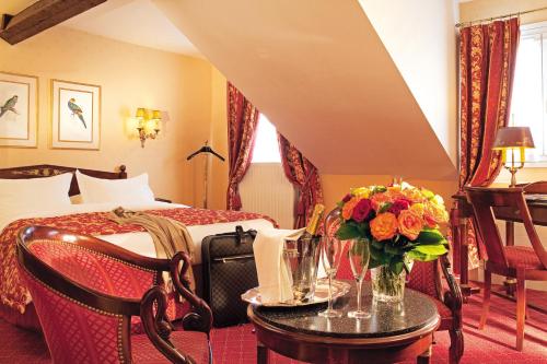 a hotel room with a bed and a table with flowers at Hôtel de Varenne in Paris