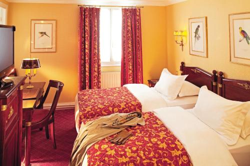 a hotel room with two beds and a desk at Hôtel de Varenne in Paris
