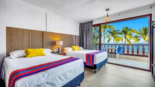 a hotel room with two beds and a balcony at Marboka Hotel & Suites in Puerto Vallarta