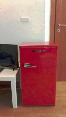 a red refrigerator sitting next to a white desk at La Quercia Fiorita in Trivolzio