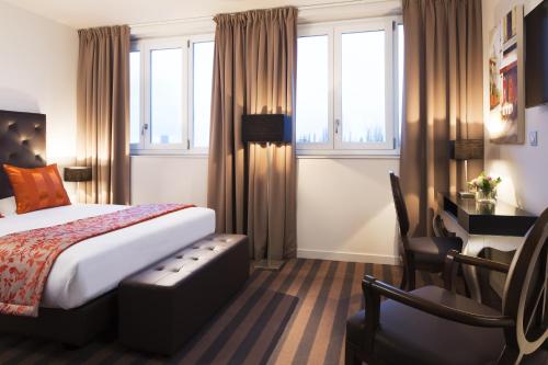 ジュヌヴィリエにあるエグゼクティブ ホテル パリ ジェヌヴィリエのベッドとデスクが備わるホテルルームです。