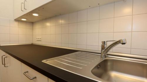 a kitchen with a stainless steel sink and white tiles at Gästezimmer Hof Stallegg in Löffingen
