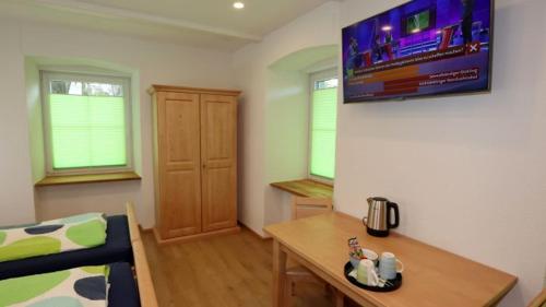 a living room with a table and a tv on the wall at Gästezimmer Hof Stallegg in Löffingen
