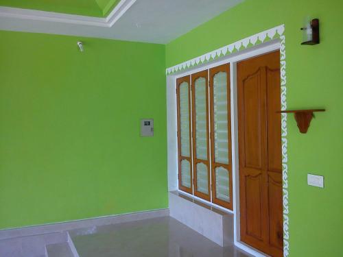 a room with green walls and a wooden door at Sajeev Home Stay in Cherai Beach