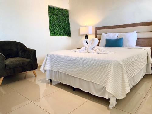 a bedroom with a white bed with a chair and a lamp at Paradise Surf Hotel in San Miguel
