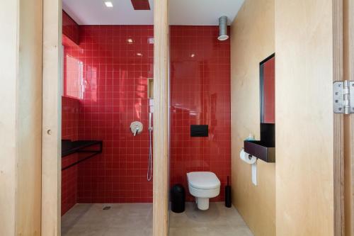 uma casa de banho com um WC e um chuveiro com azulejos vermelhos em QUIRKY em Il-Gżira