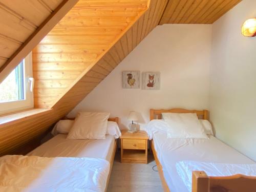 two beds in a room with wooden ceilings at Le 103. Chalet 3 chambres. Terrasse. Parking. wifi. in Cauterets