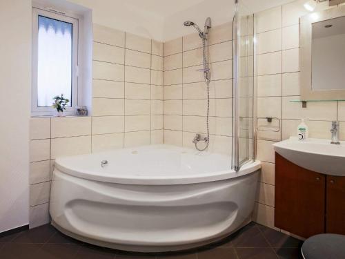 a white bath tub in a bathroom with a sink at 11 person holiday home in V ggerl se in Marielyst