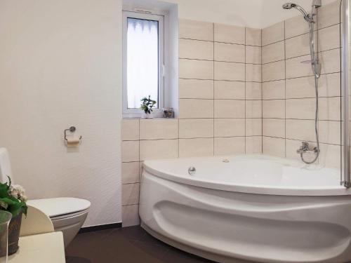 a white bathroom with a tub and a toilet at 11 person holiday home in V ggerl se in Marielyst