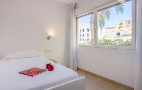 1 dormitorio con cama con libro y ventana en 3 Bedroom Gorgeous Apartment In Denia en Dénia
