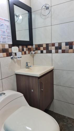a bathroom with a toilet and a sink and a mirror at HOSTERÍA BRISAS DEL RÍO in Marinilla