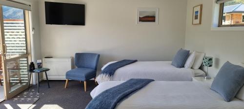 a room with two beds and a tv and a chair at Lodges on Pearson - Unit 2 in Cromwell