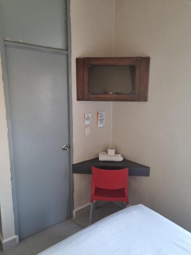 Cette chambre comprend un lit et un bureau avec une chaise rouge. dans l'établissement Hotel Victoria, à Monterrey