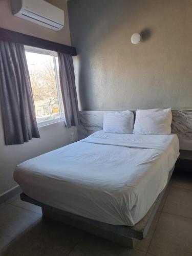 a bedroom with a large bed with a window at Hotel Victoria in Monterrey