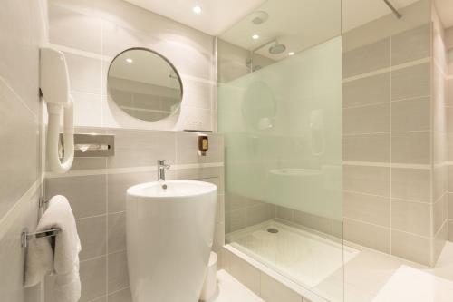 uma casa de banho com um lavatório, um chuveiro e um espelho. em Hôtel Amirauté em Toulon