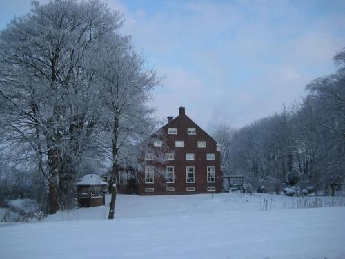 Una casa grande con nieve en el suelo delante en Wellness Sauna Beauty Farm Midwolda, en Midwolda