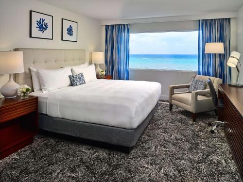 a bedroom with a bed and a window with the ocean at Sonesta Fort Lauderdale Beach in Fort Lauderdale