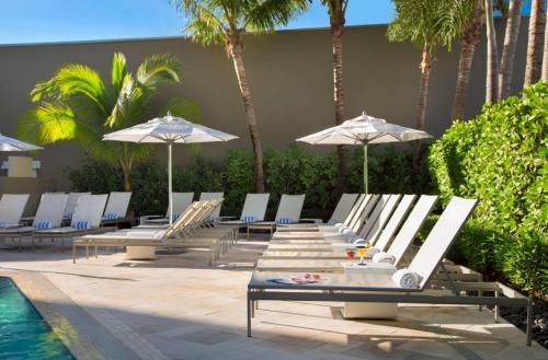 a row of lounge chairs and umbrellas next to a pool at Sonesta Fort Lauderdale Beach in Fort Lauderdale