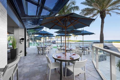 a patio with tables and chairs and umbrellas at Sonesta Fort Lauderdale Beach in Fort Lauderdale