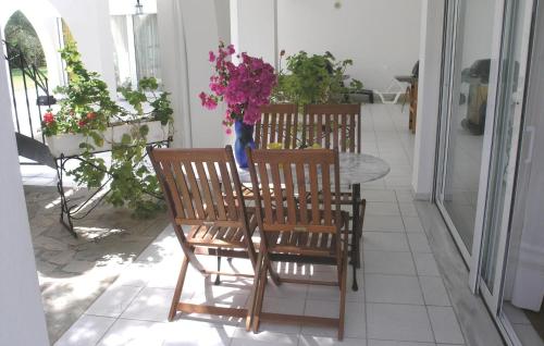 a table with three chairs and a vase of flowers at Soleiliosonne Haus Europa in Ermioni