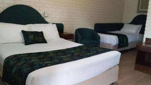 a hotel room with two beds and a chair at Macquarie Valley Motor Inn in Warren