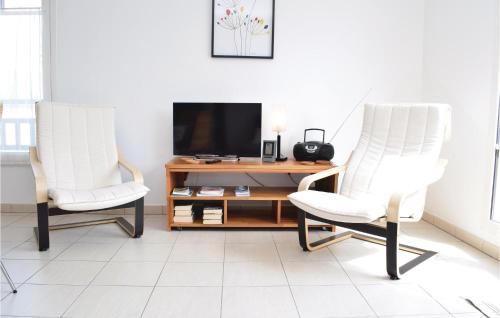 2 chaises blanches assises à côté d'un bureau avec une télévision dans l'établissement Amazing Apartment In Hauteville-Sur-Mer, à Hauteville-sur-Mer