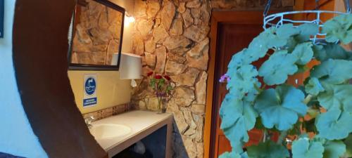 baño con lavabo y pared de piedra en Villa del Rosario Hostal, en Cuenca