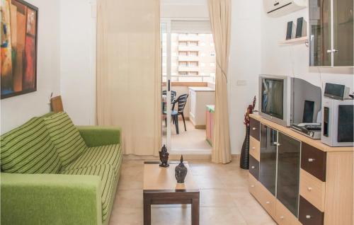 a living room with a green couch and a tv at Cozy Apartment In Oropesa Del Mar in Oropesa del Mar