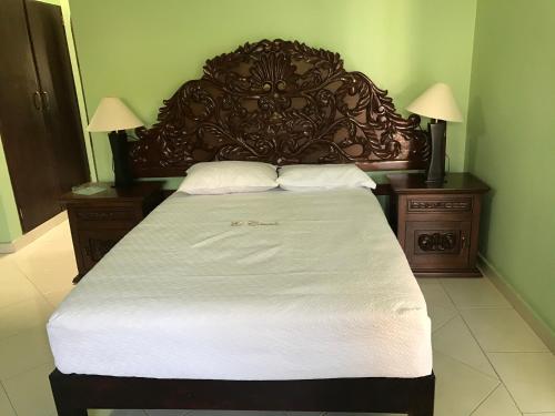 ein großes Bett mit einem Kopfteil aus Holz und zwei Nachttischen in der Unterkunft Villa familiar El Ciruelo in Cuernavaca