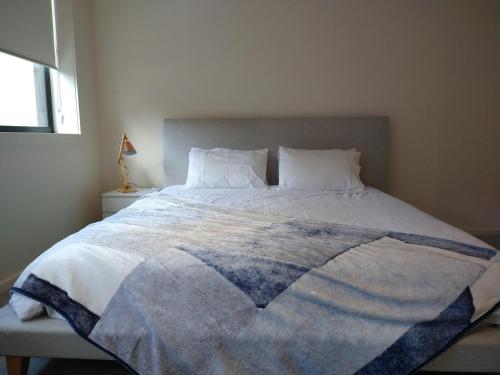 a bed with a blue and white blanket on it at Brand New Spacious Woden Apartment - KingBed&WiFi in Phillip