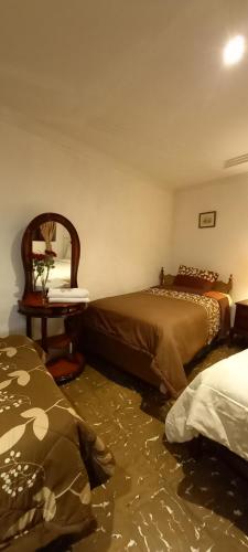 Villa del Rosario Hostal في كوينكا: غرفة بسريرين وطاولة مع مرآة