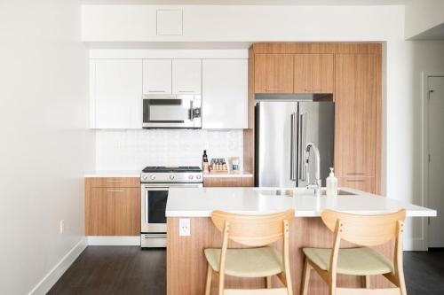 a kitchen with a white counter and a refrigerator at Skyline Blue Modern Loft - Zuni Lofts in Denver