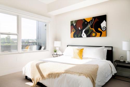 a white bedroom with a bed and a painting on the wall at City views - Luxe Loft - Zuni Lofts in Denver