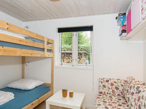GlesborgにあるHoliday home Glesborg XLIVの二段ベッドとソファが備わる小さな客室です。
