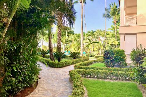 een tuin met palmbomen en een loopbrug bij La Dolce Vita Beachfront Apt 2 in Las Terrenas